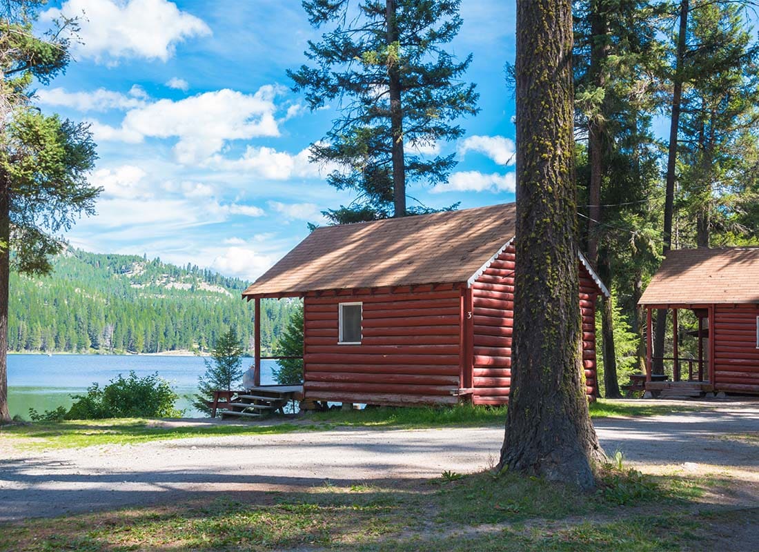 Tonasket, WA - Small Red Cabins Facing the Lake Surrounded by Pine Trees in Tonasket Washington